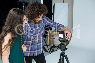 Photographer and female model reviewing captured photos in digital camera