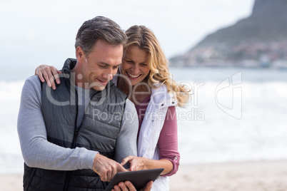 Mature couple using digital table on the beach