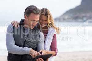 Mature couple using digital table on the beach