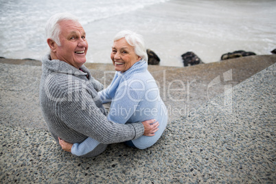 Senior couple sitting on rock at beach