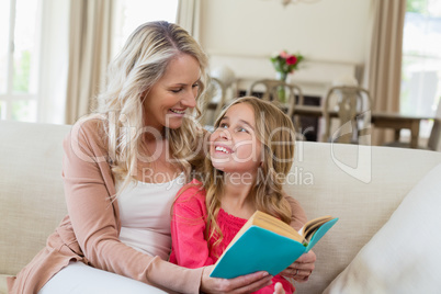 Mother and daughter reading a novel on the couch