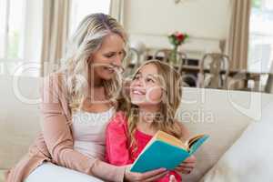 Mother and daughter reading a novel on the couch