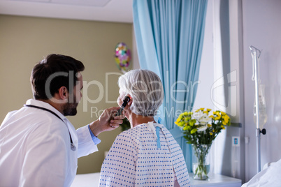 Doctor examining patients ear with otoscope