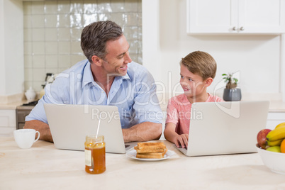 Father and son using laptop in kitchen