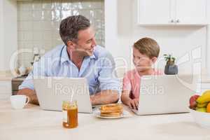 Father and son using laptop in kitchen