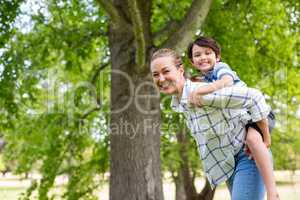 Mother giving a piggyback ride to his son in park