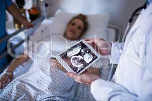 Male doctor looking at sonography report on a digital tablet