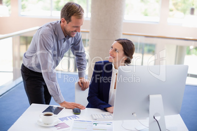 Businesswoman working at desk with colleague
