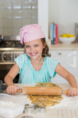 Girl sheeting the dough with a rolling pin in the kitchen