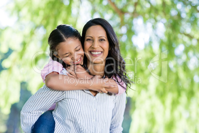 Happy mother giving piggyback ride to her daughter