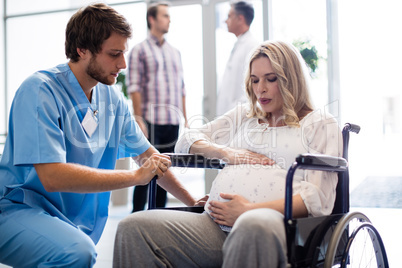 Male doctor talking to pregnant woman in wheelchair