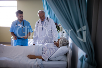 Doctors comforting senior patient on bed