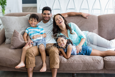 Portrait of parents and kids sitting on sofa in living room