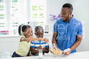 Father giving cookies to kids