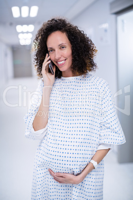 Pregnant woman talking on mobile phones in corridor