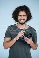Happy photographer holding a camera in the studio
