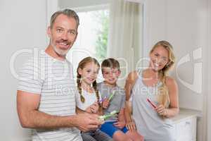Portrait of parents and kids brushing teeth in bathroom