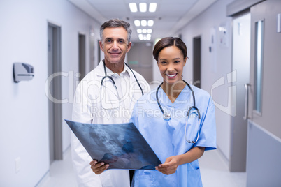 Portrait of doctors examining x-ray in corridor