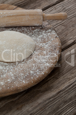 Rolling pin with pizza dough and flour on rolling board