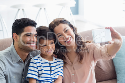 Parents and son taking a selfie from mobile phone in living room