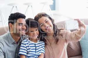 Parents and son taking a selfie from mobile phone in living room