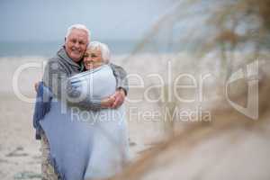 Senior couple wrapped in shawl on the beach