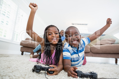 Siblings lying on rug and playing video game