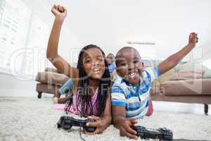 Siblings lying on rug and playing video game