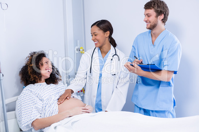 Doctors interacting with pregnant woman in ward