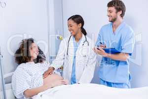 Doctors interacting with pregnant woman in ward