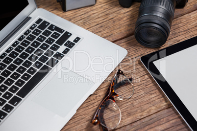 Close-up of digital camera, digital tablet, laptop, spectacle on table