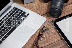 Close-up of digital camera, digital tablet, laptop, spectacle on table