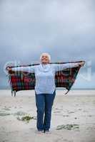 Senior woman with arms outstretched standing on the beach