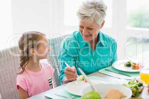 Grandmother serving a food to granddaughter
