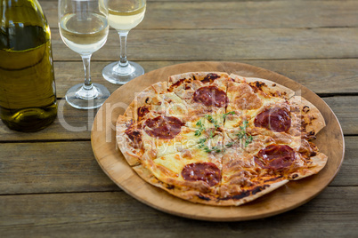Italian pizza served in a pizza tray with wine glasses
