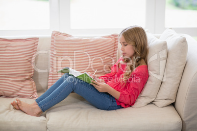 Girl sitting on sofa and doing homework in living room