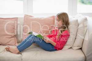 Girl sitting on sofa and doing homework in living room