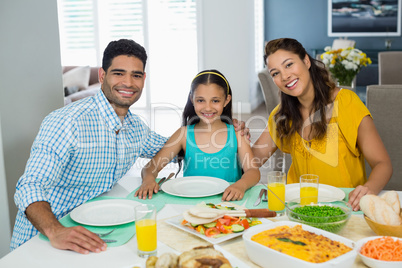 Daughter and parents having meal on table at home