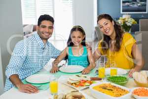 Daughter and parents having meal on table at home