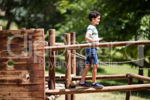 Boy walking on a playground ride in park