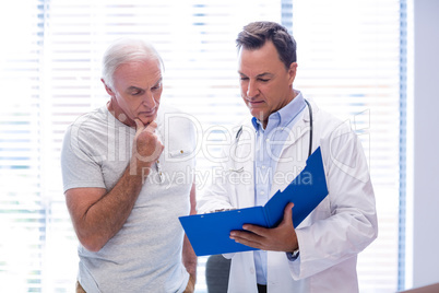 Doctor and senior man discussing on file