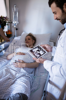 Male doctor looking at sonography report on a digital tablet