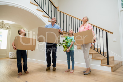 Parents and kids holding cardboard boxes in living room at home