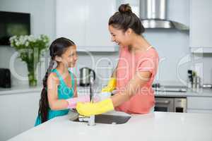 Mother assisting her daughter in cleaning vessel