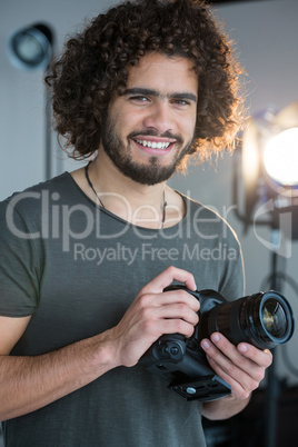 Happy photographer holding a camera in the studio