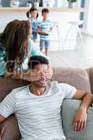 Woman covering man eyes while giving surprise in living room