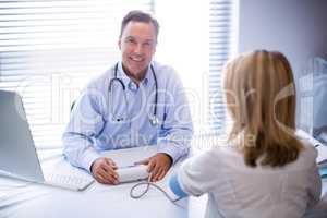 Portrait of doctor checking blood pressure of a patient