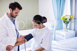 Male doctor checking blood pressure of a female patient