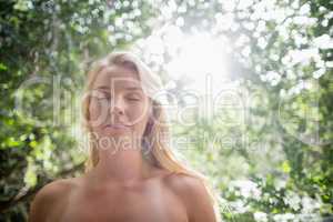 Beautiful woman meditating against bright sunlight