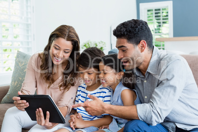 Parents and kids using digital tablet in living room